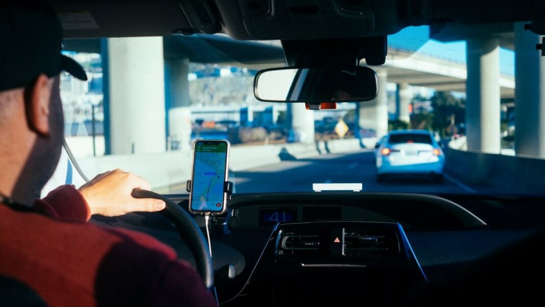 car rental represented by a photo from behind of a man driving a car in an urban setting