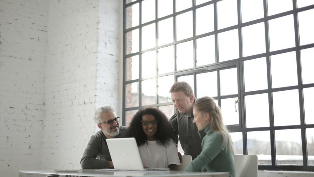 developers represented by a group of four people sitting at a table in a room with white walls and a large window