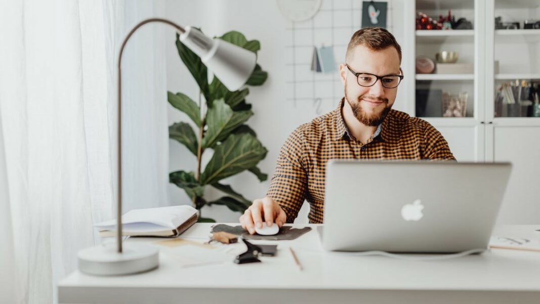 home-based business represented by a smiling man viewing an open laptop