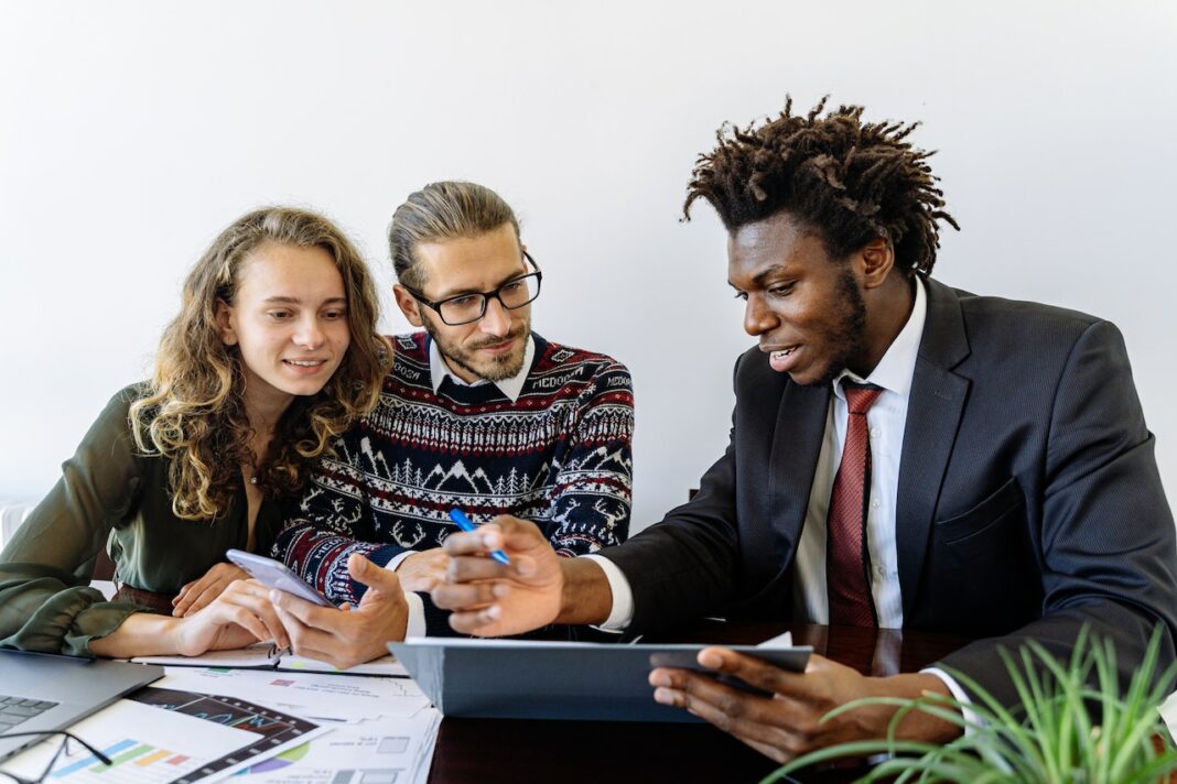 young african american man pointing at laptop and speaking to a couple about lead generation